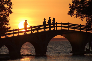 People crossing bridge at sunset